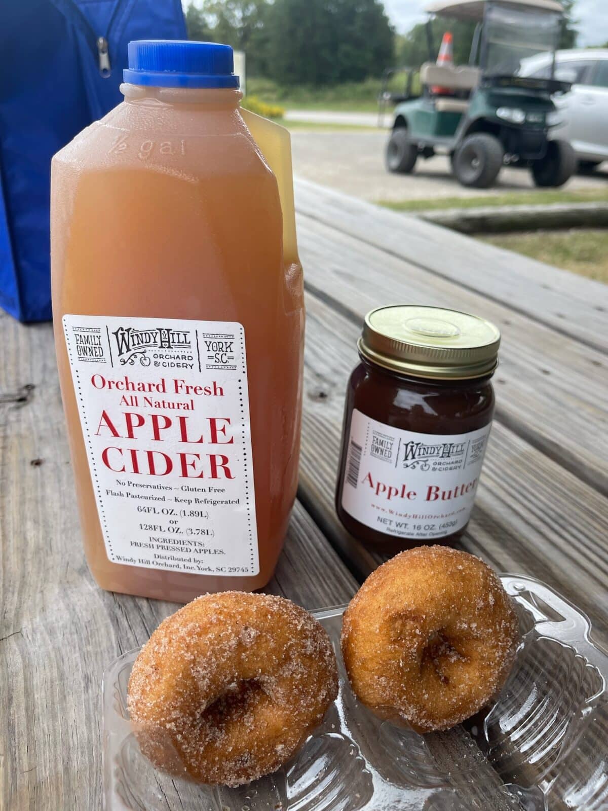 apple cider, apple butter and doughnuts displayed on a picnic table